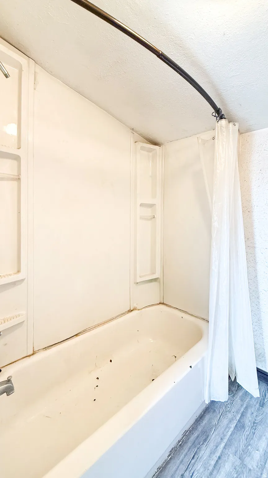 Bathroom featuring shower / bath combo, wood finished floors, and a textured ceiling in cabin.