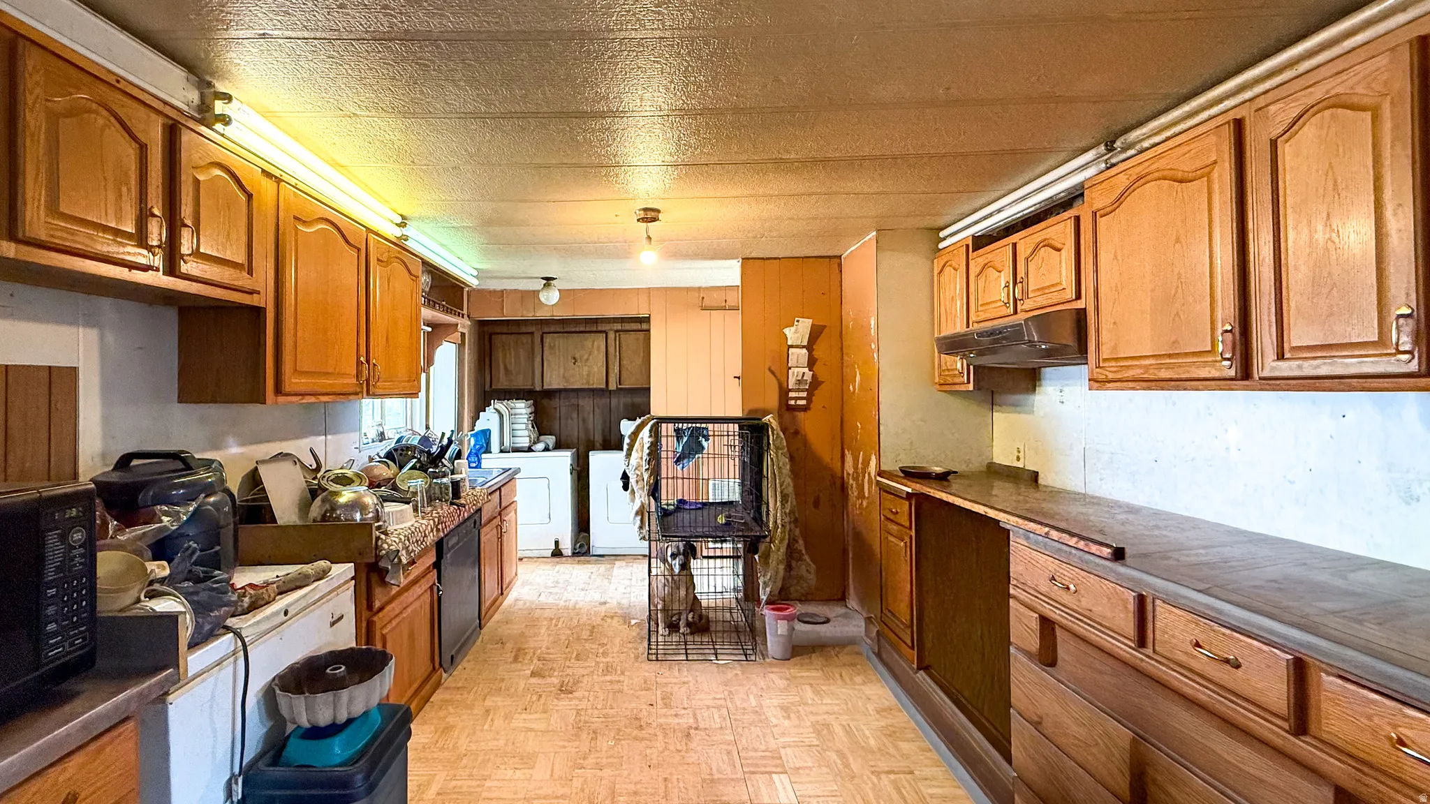 Kitchen featuring wood finish cabinets, dark countertops, black appliances, parquet floors, and separate washer and dryer