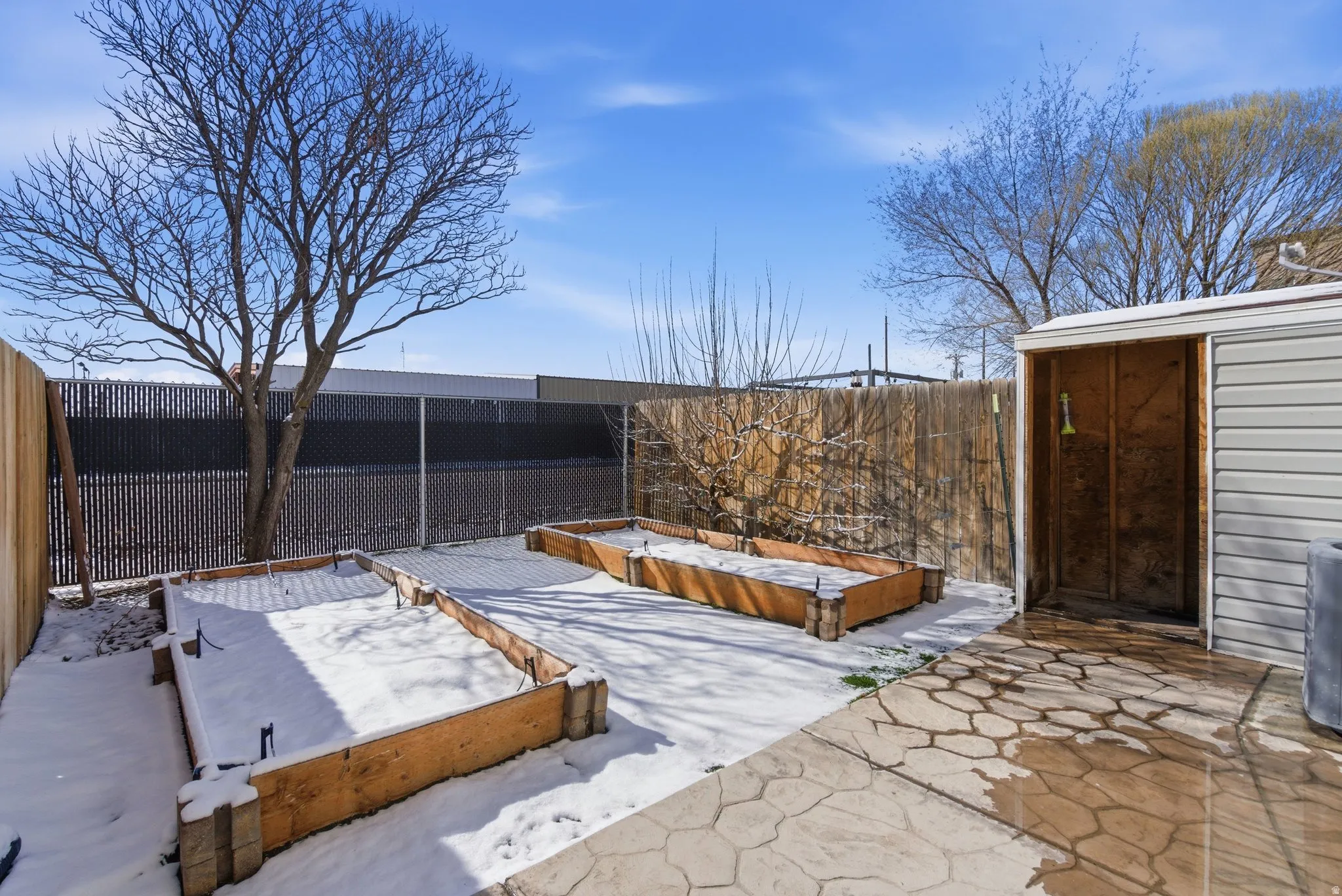 Fenced backyard with a garden, a patio area, and a storage shed