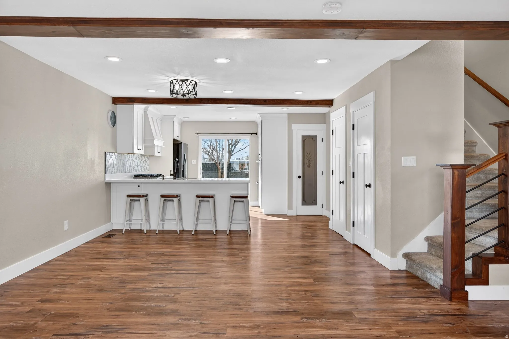 Kitchen with light countertops, a breakfast bar area, white cabinetry, dark wood-style floors, and recessed lighting