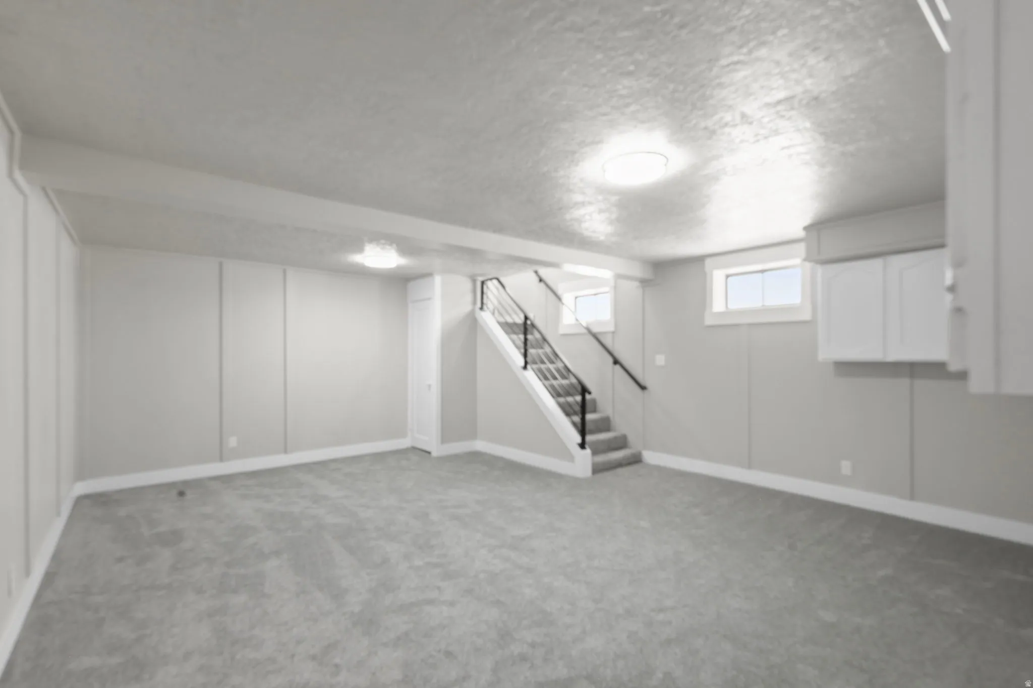 Basement with light colored carpet and a textured ceiling
