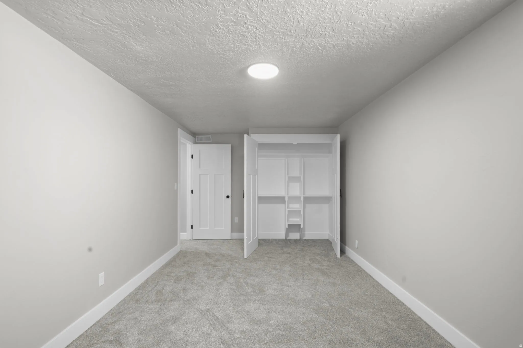 Unfurnished bedroom with carpet floors, a textured ceiling, and a closet