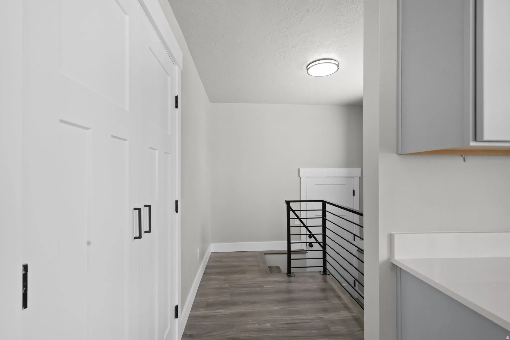 Hall with an upstairs landing, dark wood-type flooring, and a textured ceiling