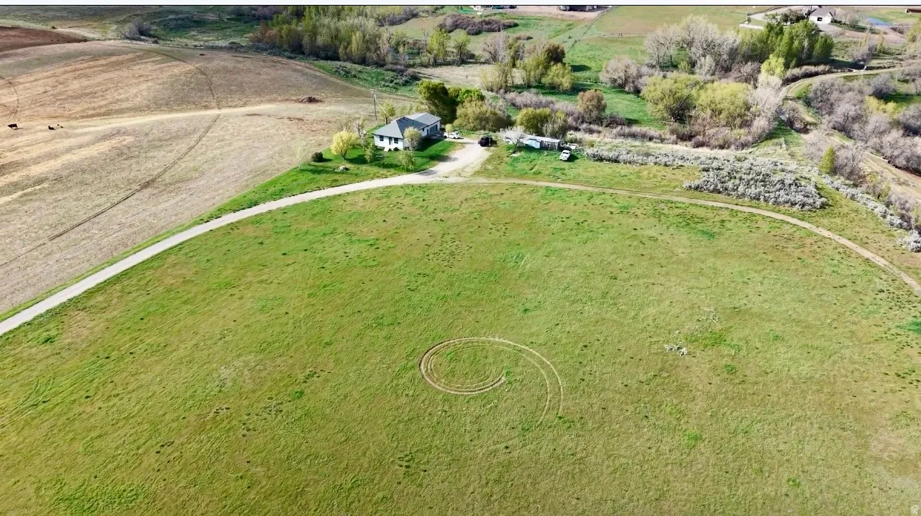 Expansive green pastureland with a winding drive leading to a single-story residence