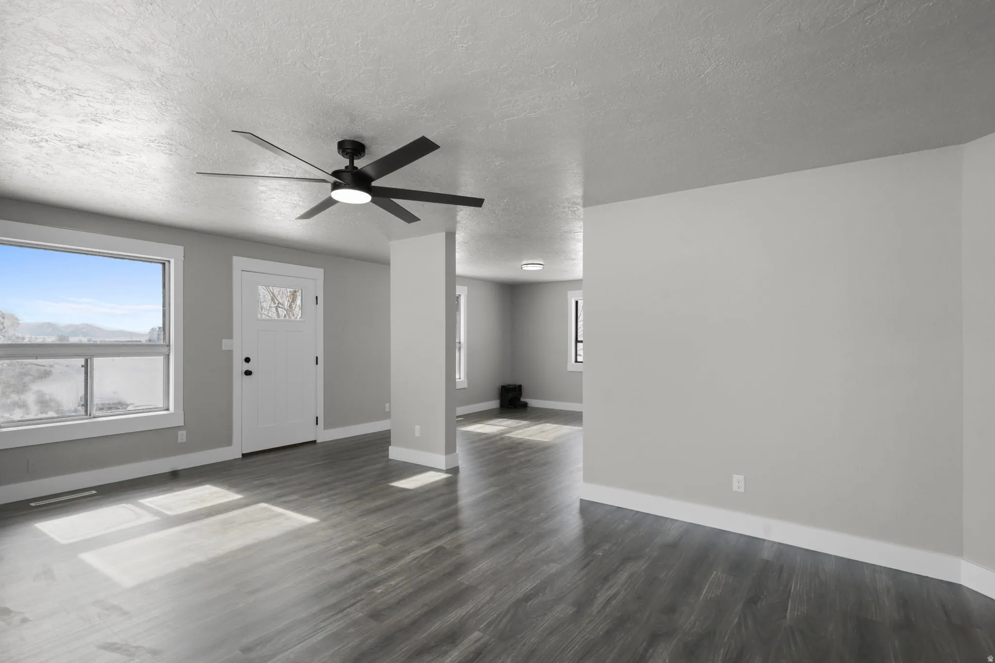 Entryway with a ceiling fan, dark wood-style floors, and a textured ceiling