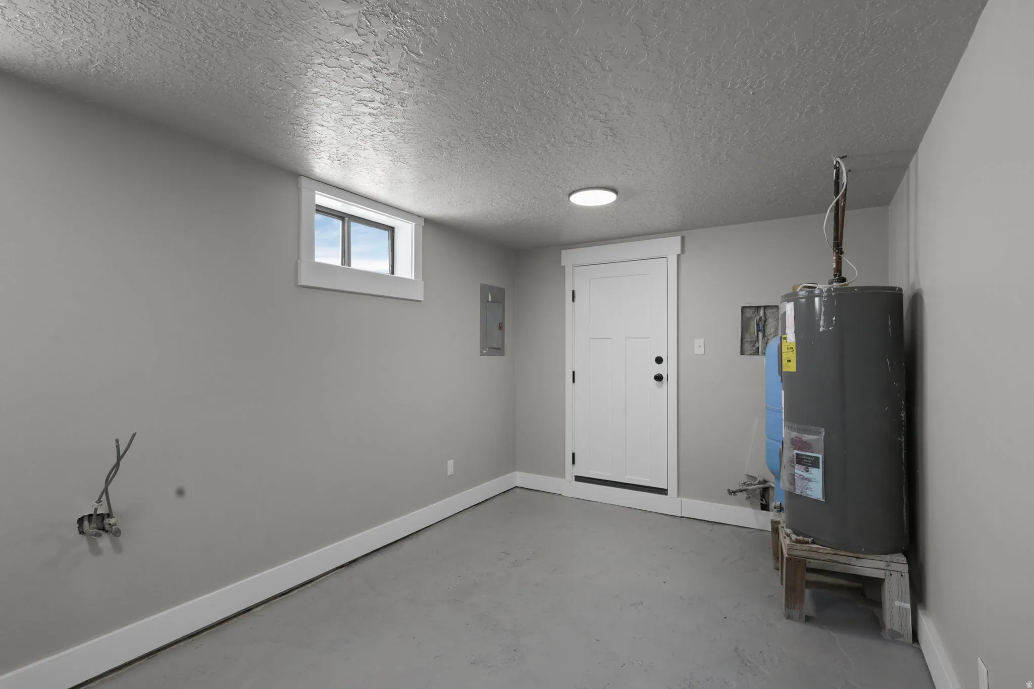Below grade area featuring water heater, a textured ceiling, and electric panel
