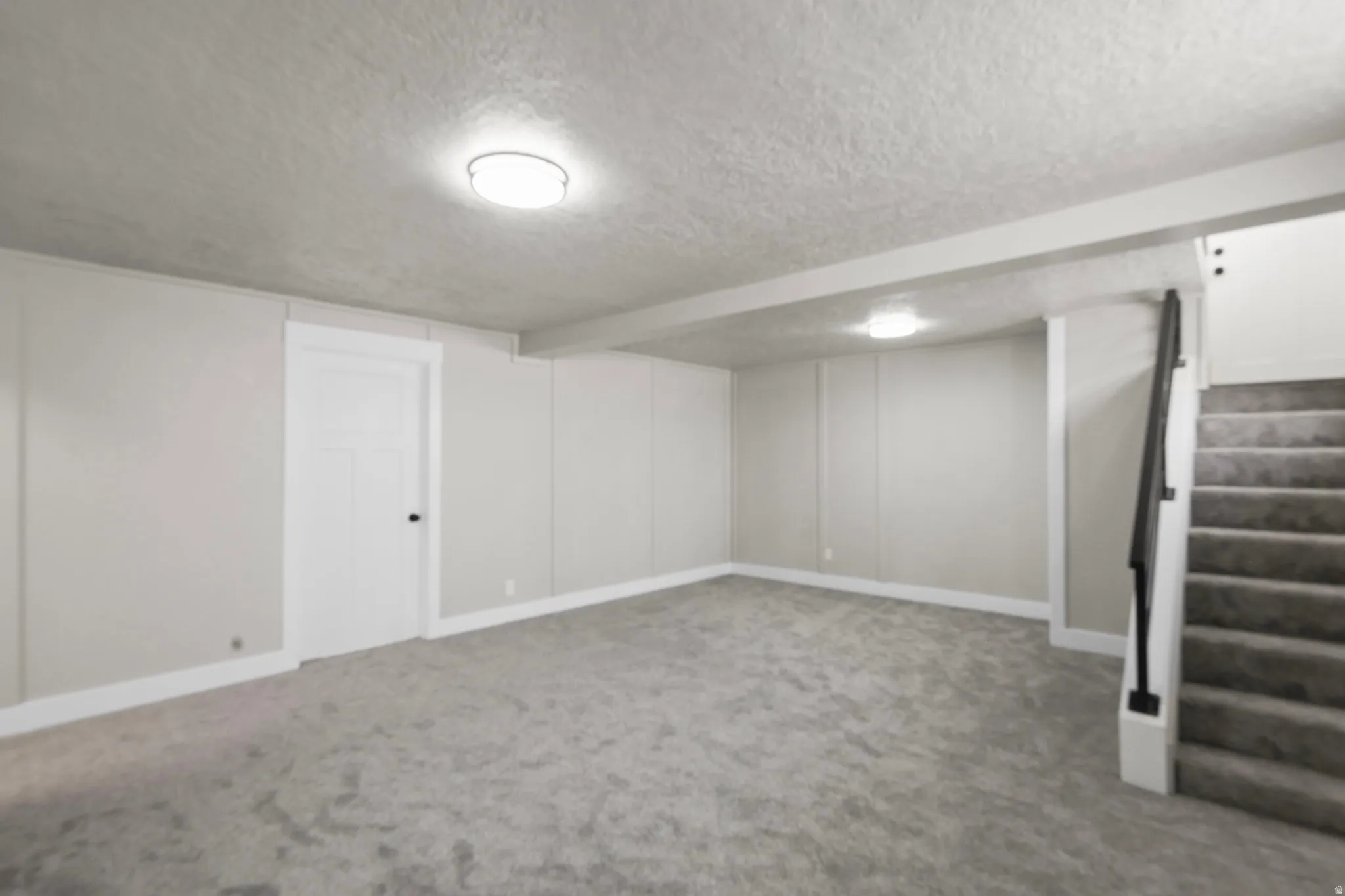 Finished basement with a textured ceiling and carpet floors