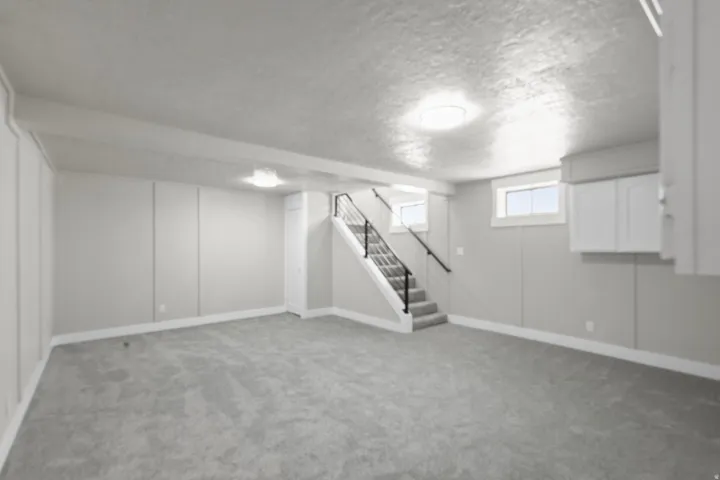 Basement with light colored carpet and a textured ceiling