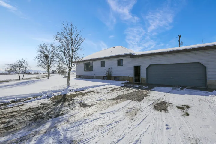 Snow covered rear of property featuring an attached garage