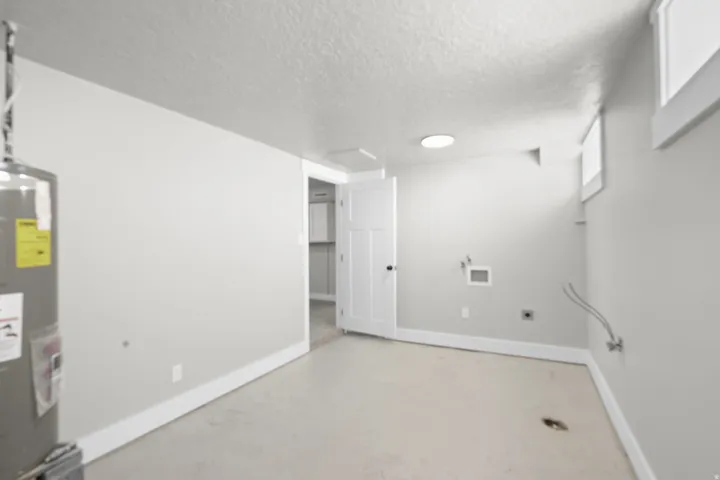 Basement featuring a textured ceiling and electric water heater