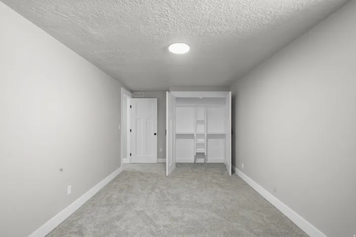 Unfurnished bedroom with carpet floors, a textured ceiling, and a closet