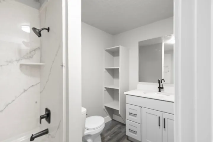Full bathroom featuring vanity, a combined bath / shower with marble appearance, and dark wood-style floors