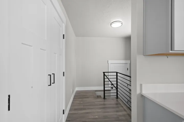 Hall with an upstairs landing, dark wood-type flooring, and a textured ceiling
