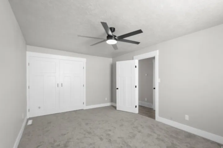 Unfurnished bedroom with carpet floors, ceiling fan, a textured ceiling, and a closet