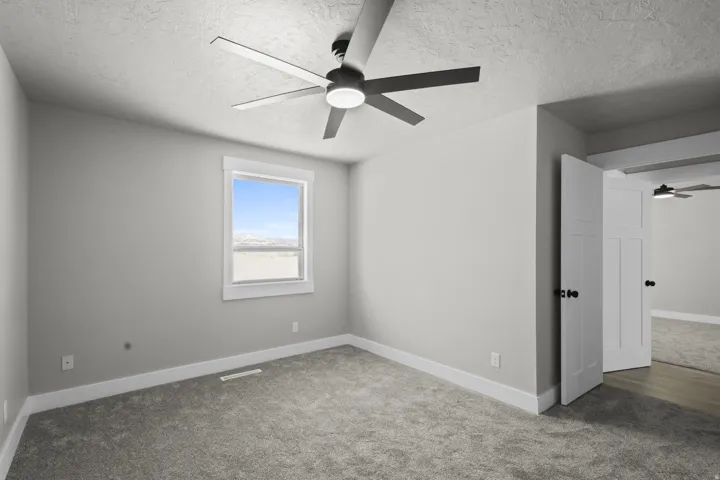 Carpeted spare room with a ceiling fan and a textured ceiling