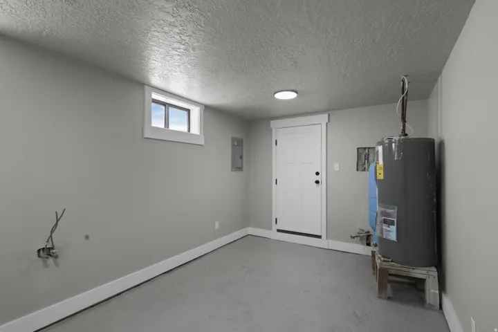 Below grade area featuring water heater, a textured ceiling, and electric panel