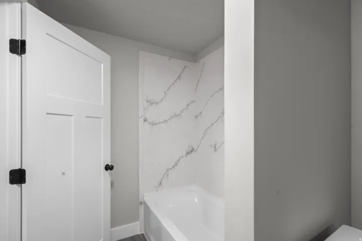 Full bath featuring a tub to relax in and baseboards