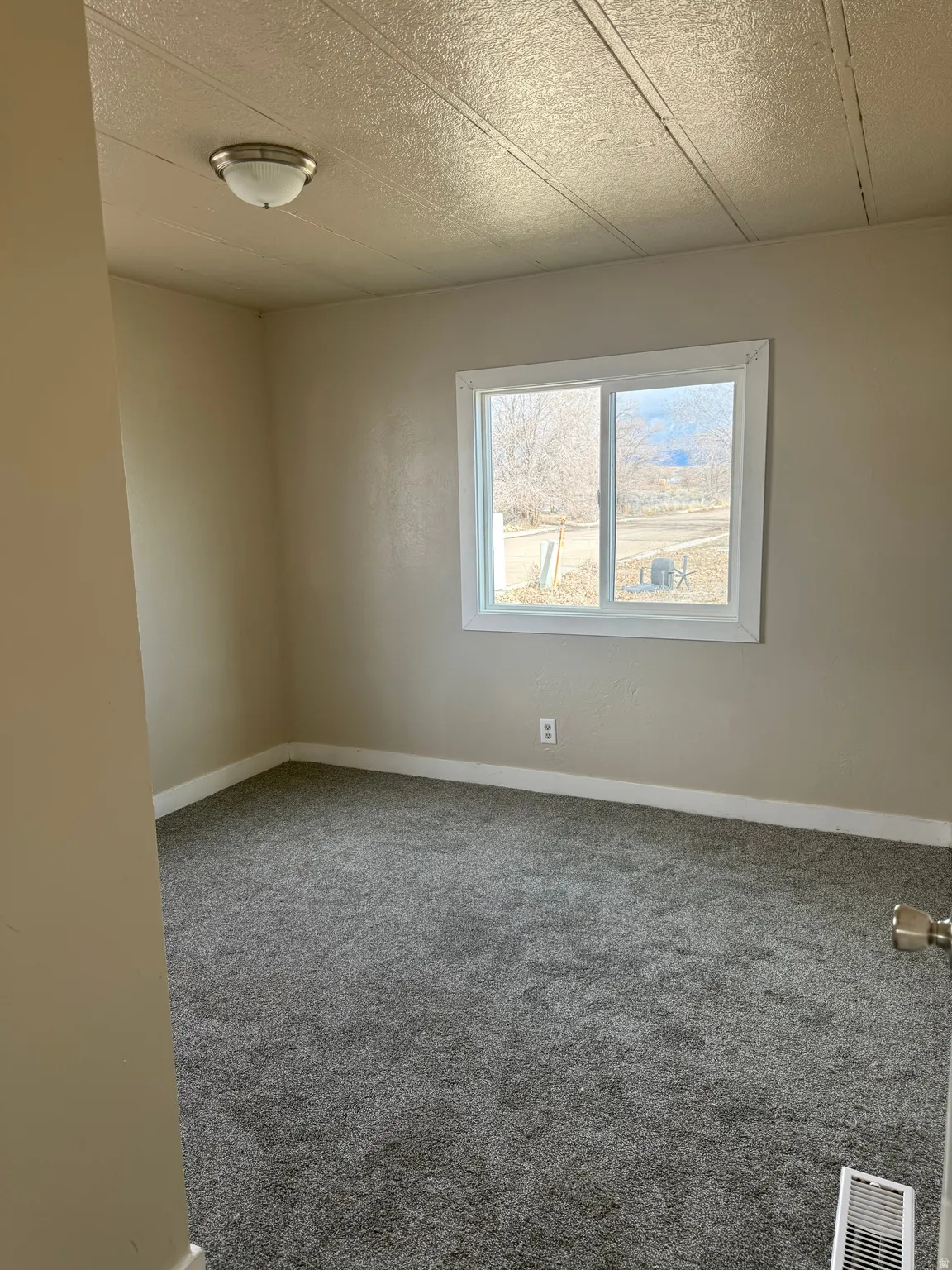 Empty room featuring carpet and a textured ceiling