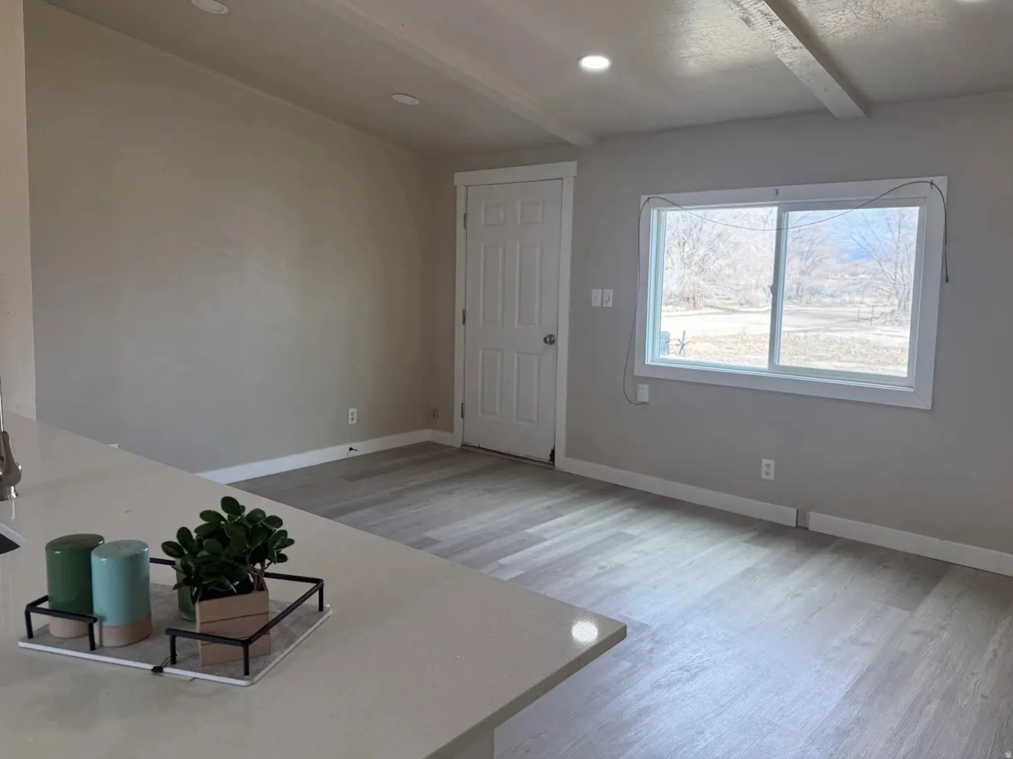 Unfurnished living room with light wood-type flooring, beam ceiling, and recessed lighting