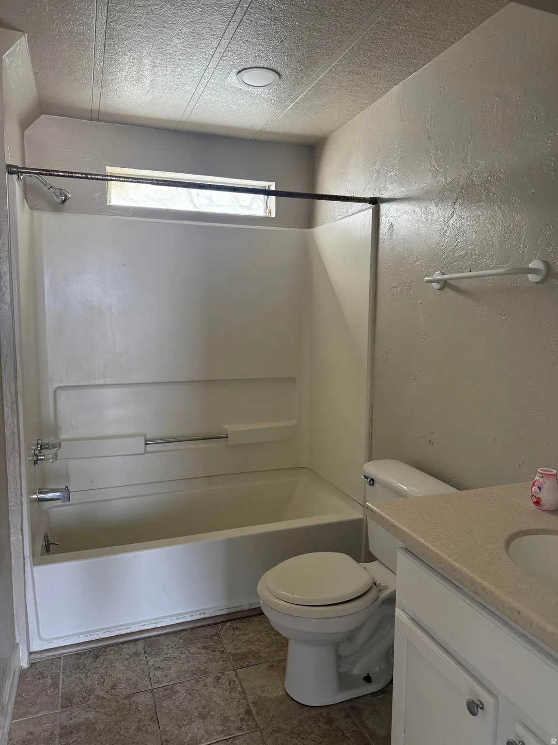 Full bathroom with a textured wall, vanity, shower / washtub combination, and a textured ceiling
