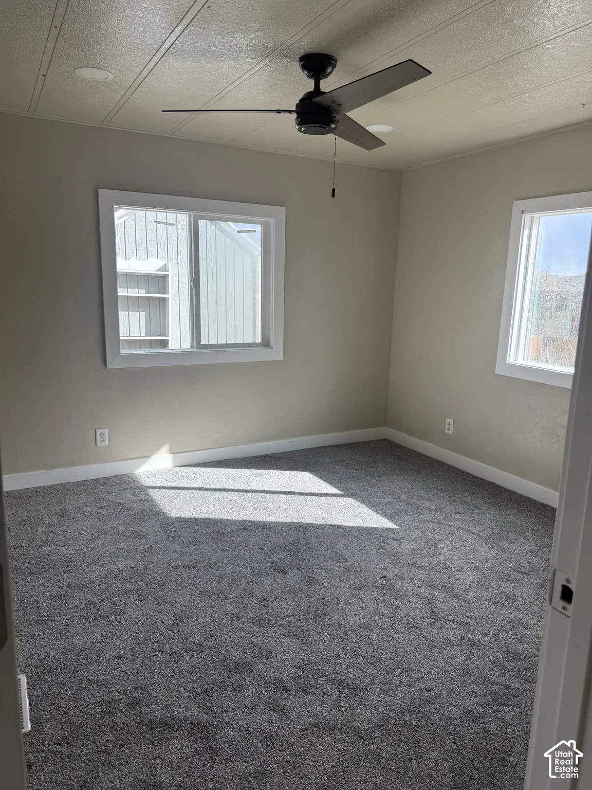 Carpeted spare room featuring a ceiling fan and a textured ceiling