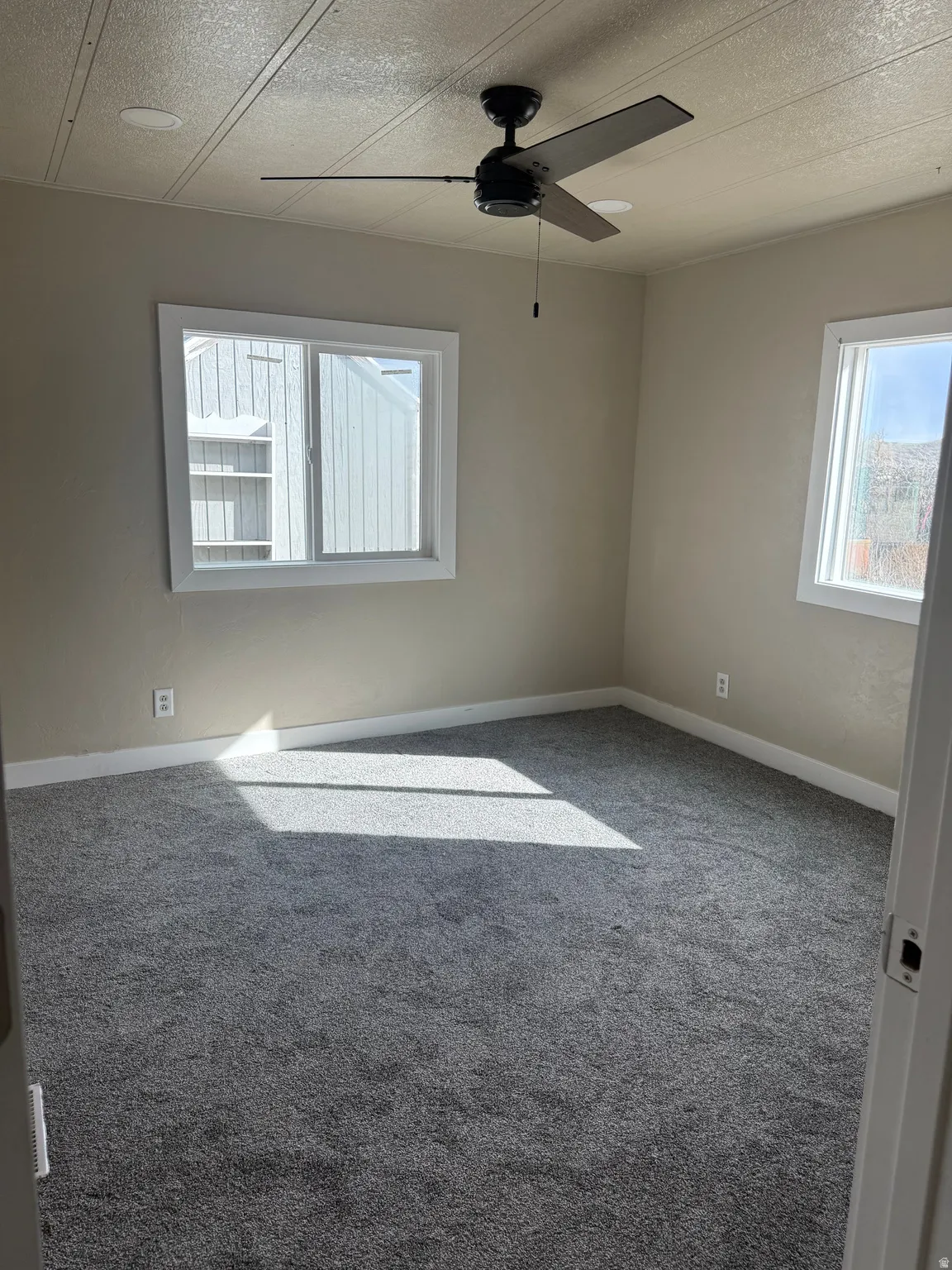 Carpeted spare room featuring a ceiling fan and a textured ceiling