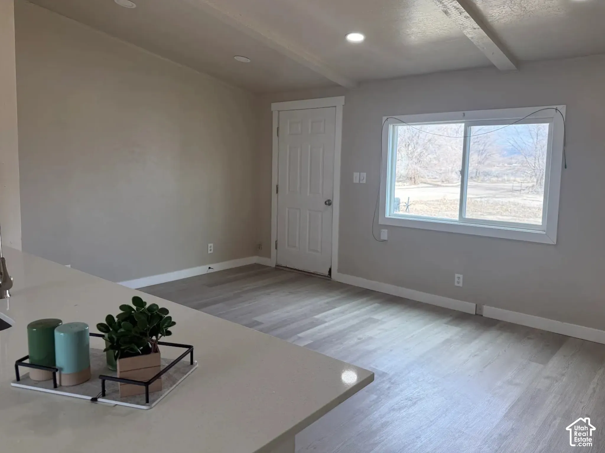 Unfurnished living room with light wood-type flooring, beam ceiling, and recessed lighting