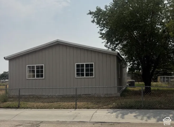 Gray vertical siding exterior with white-framed windows and a chain-link fence