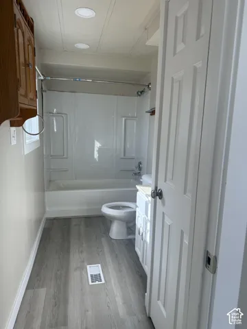 Full bathroom featuring vanity, shower / bath combination, and light wood-style floors