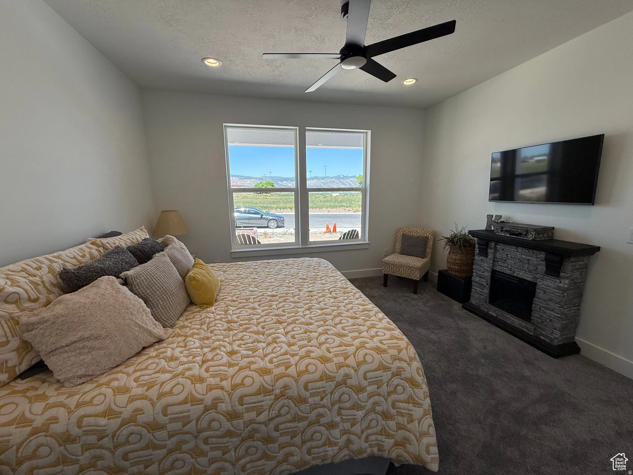 Bedroom with dark colored carpet, a fireplace, ceiling fan, recessed lighting, and a textured ceiling