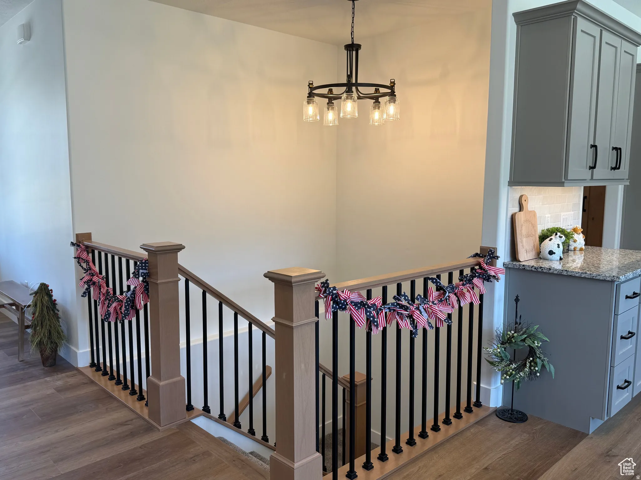Stairs featuring wood finished floors and suspended lighting