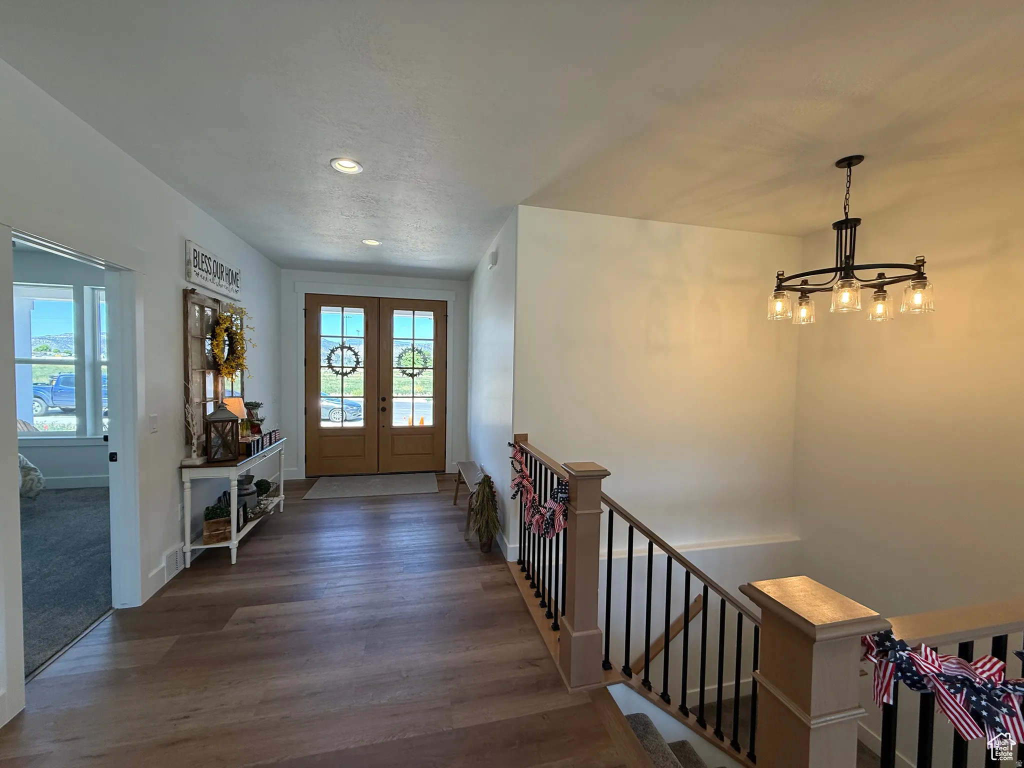 Foyer with wood finished floors, french doors, and hanging lights