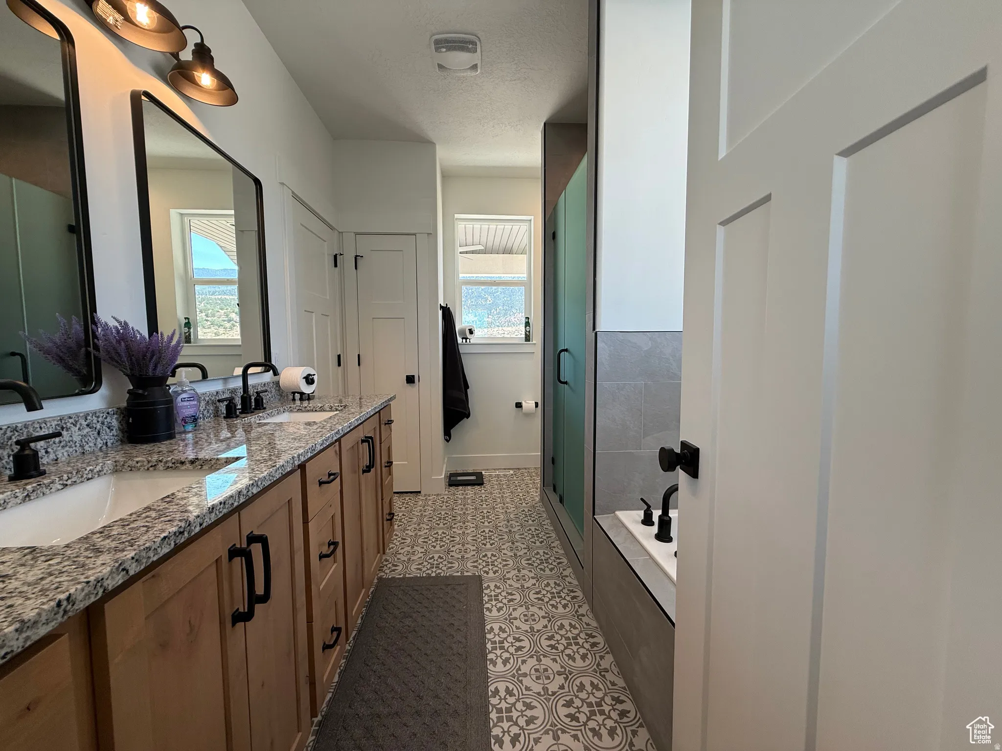Full bath with double vanity, a garden tub, a shower stall, and a textured ceiling