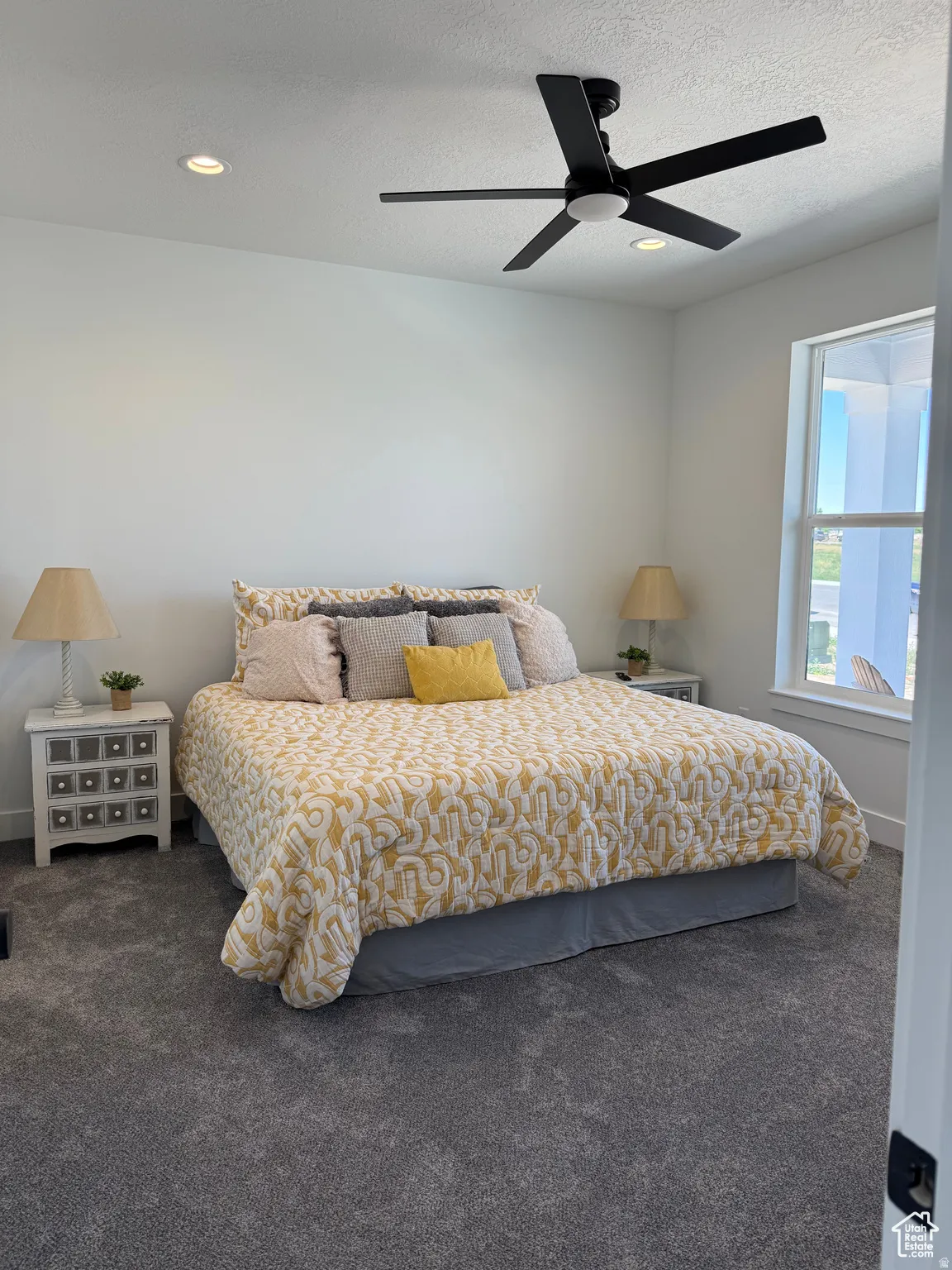 Bedroom with dark colored carpet, a ceiling fan, and a textured ceiling