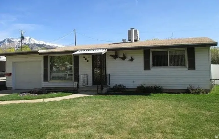 Single story home featuring a garage, a front lawn, and driveway