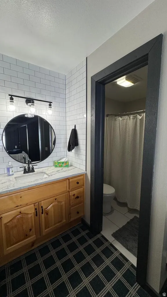 Bathroom featuring a shower with shower curtain, tasteful backsplash, vanity, and a textured ceiling