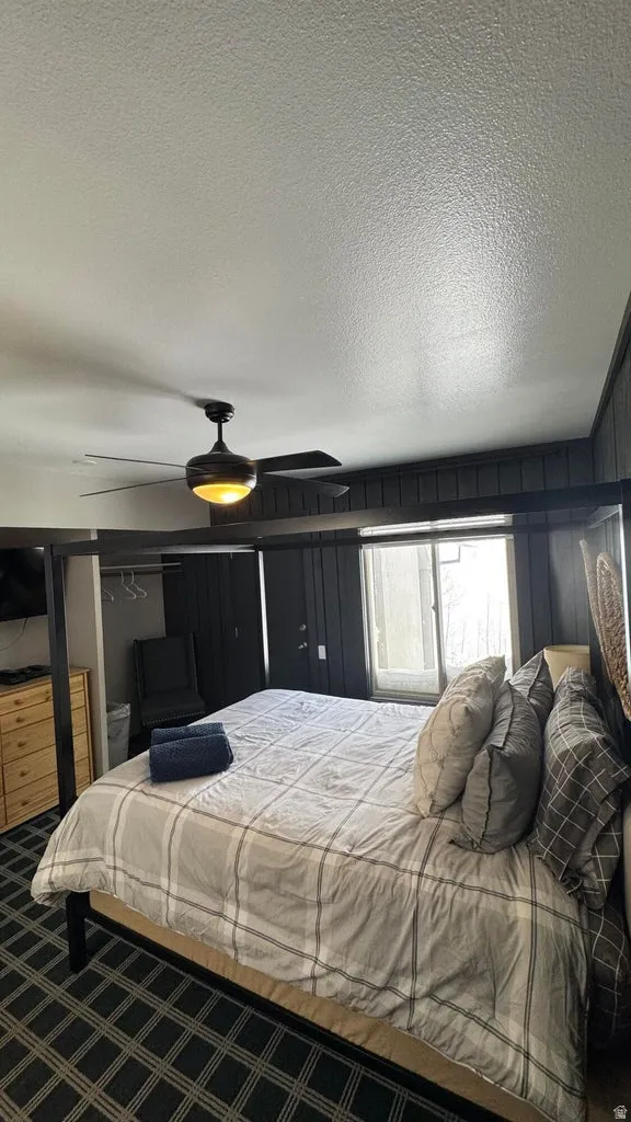 Carpeted bedroom with a textured ceiling and a ceiling fan