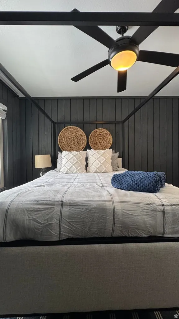 Bedroom with wood walls and ceiling fan
