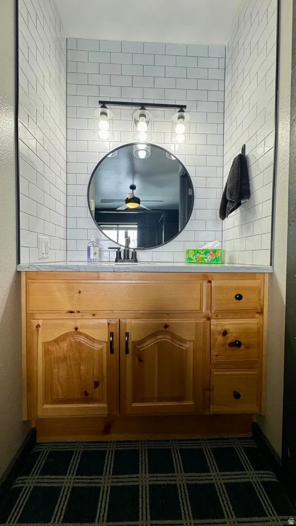 Bathroom featuring vanity, a textured wall, and backsplash