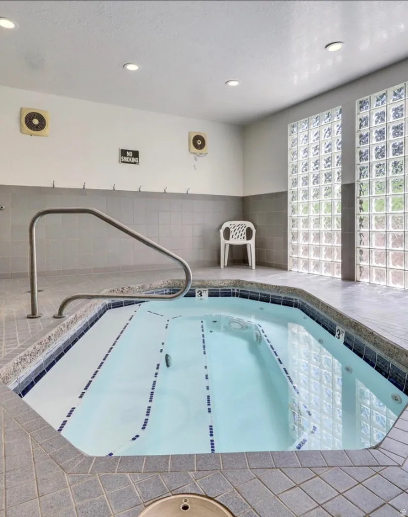 View of swimming pool with a hot tub