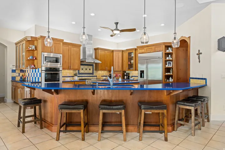 Kitchen featuring open shelves, wood finish cabinets, light tile patterned flooring, and glass insert cabinets