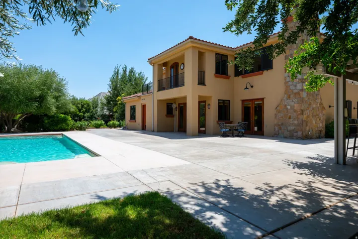 Back of house with a balcony, a tiled roof, stucco siding, an outdoor pool, and outdoor dining area