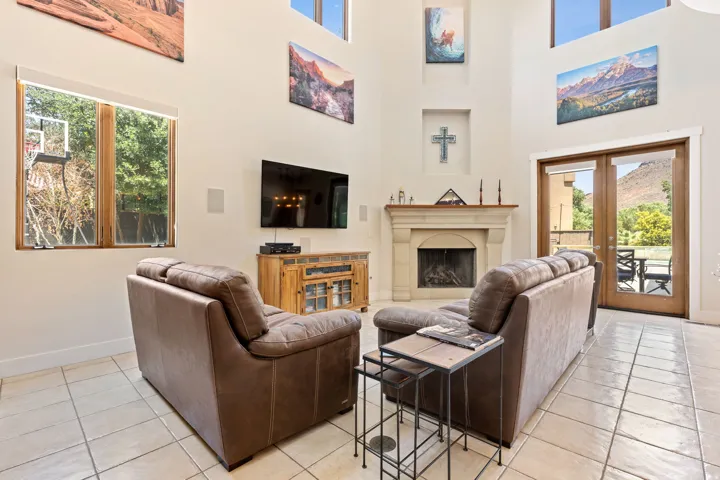 Living room featuring a fireplace, french doors, plenty of natural light, and a high ceiling