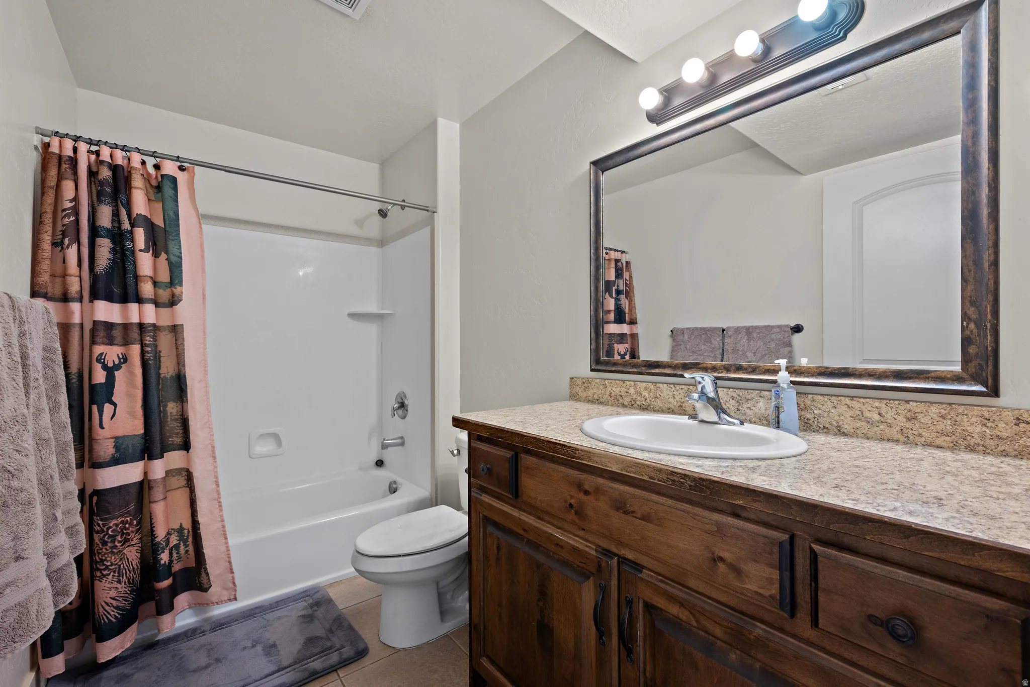 Bathroom featuring vanity, light tile patterned floors, and shower / bathtub combination with curtain