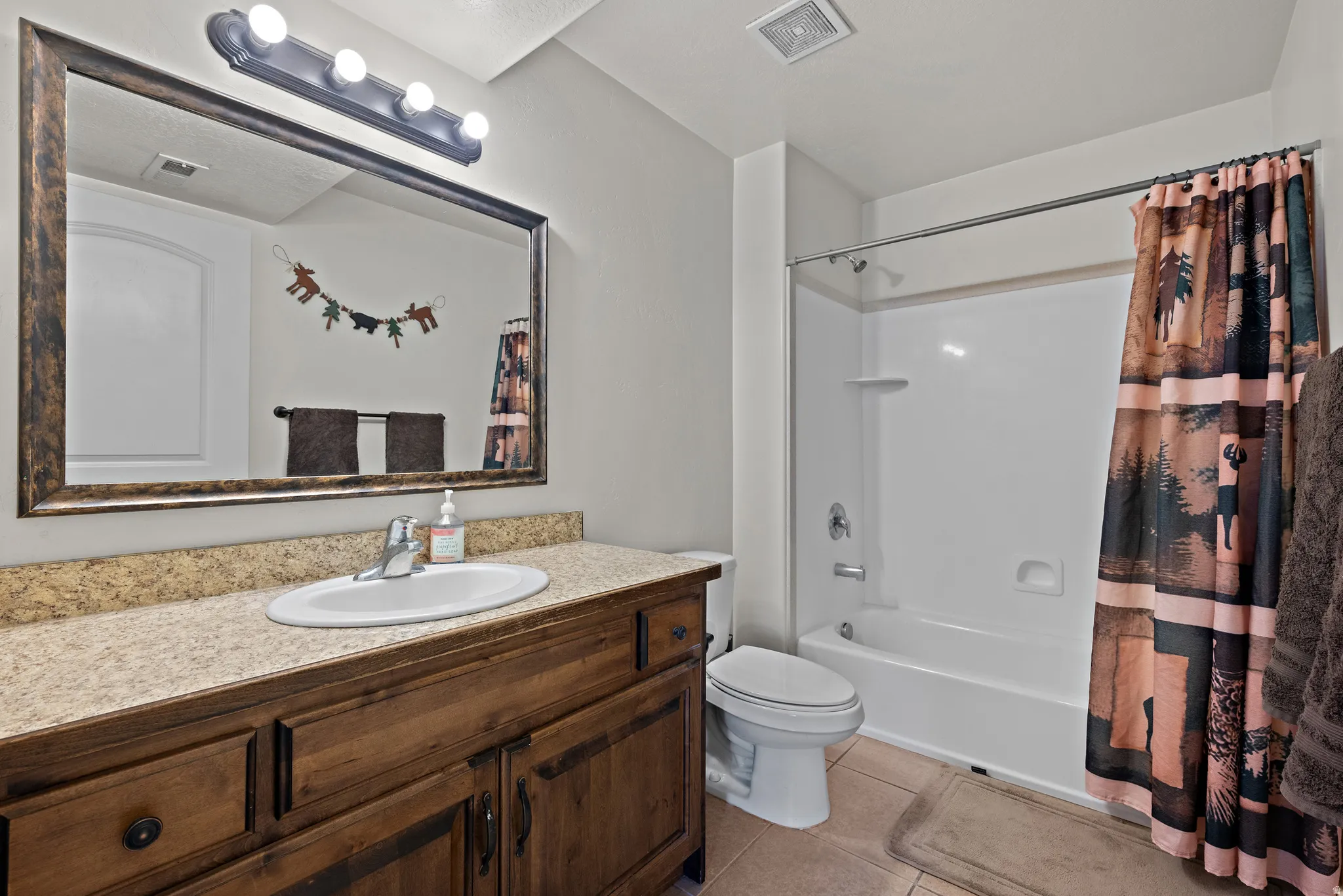 Full bath featuring vanity, shower / tub combo, and light tile patterned floors