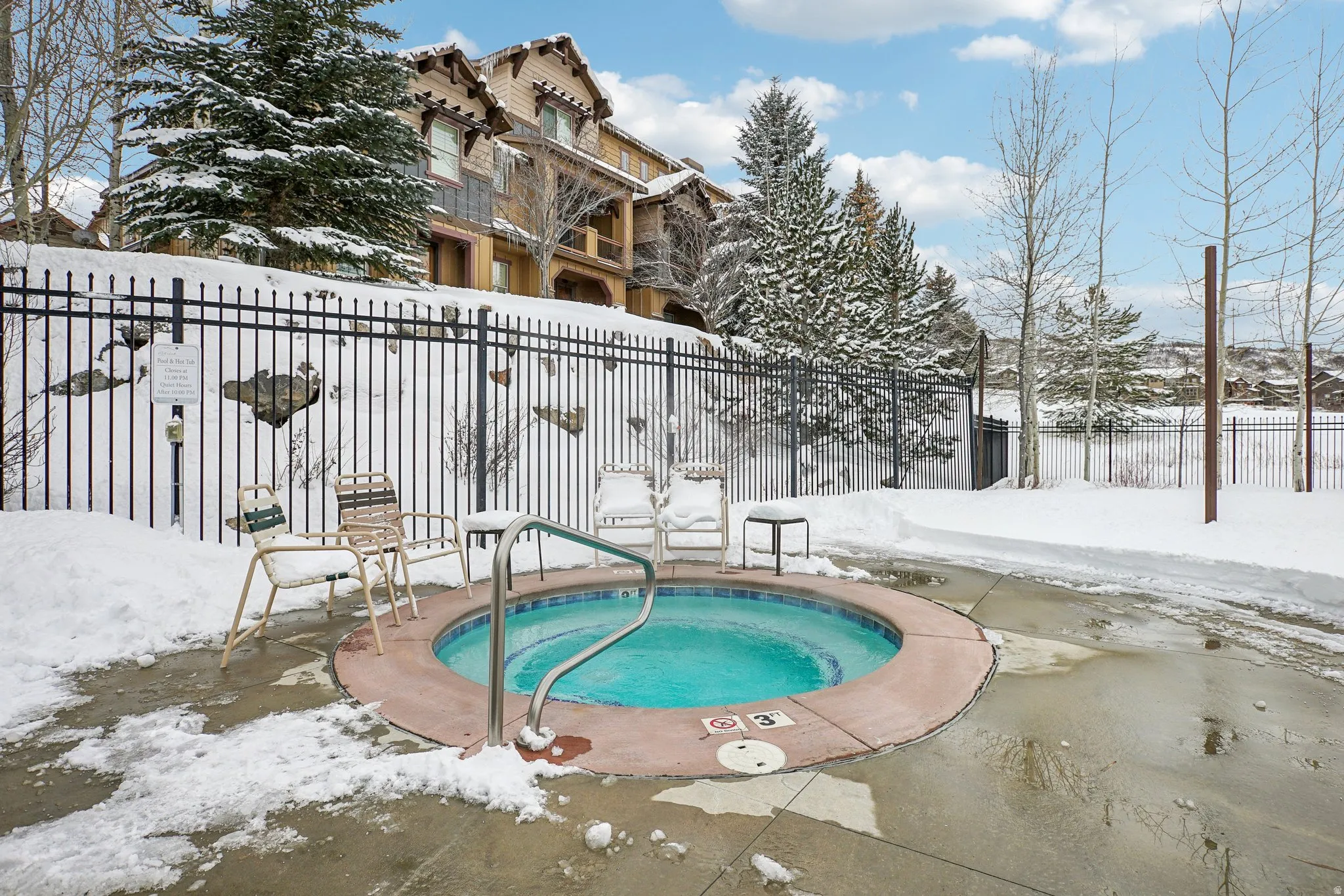 Snow covered pool with a community hot tub and a patio