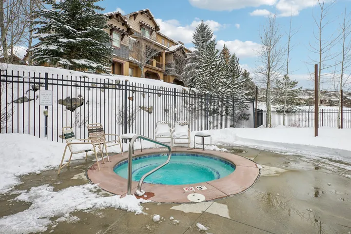 Snow covered pool with a community hot tub and a patio