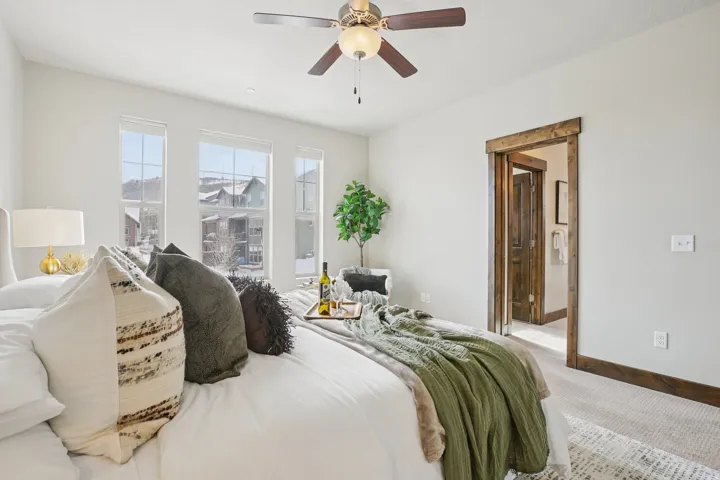 Carpeted bedroom with a ceiling fan and ensuite bath