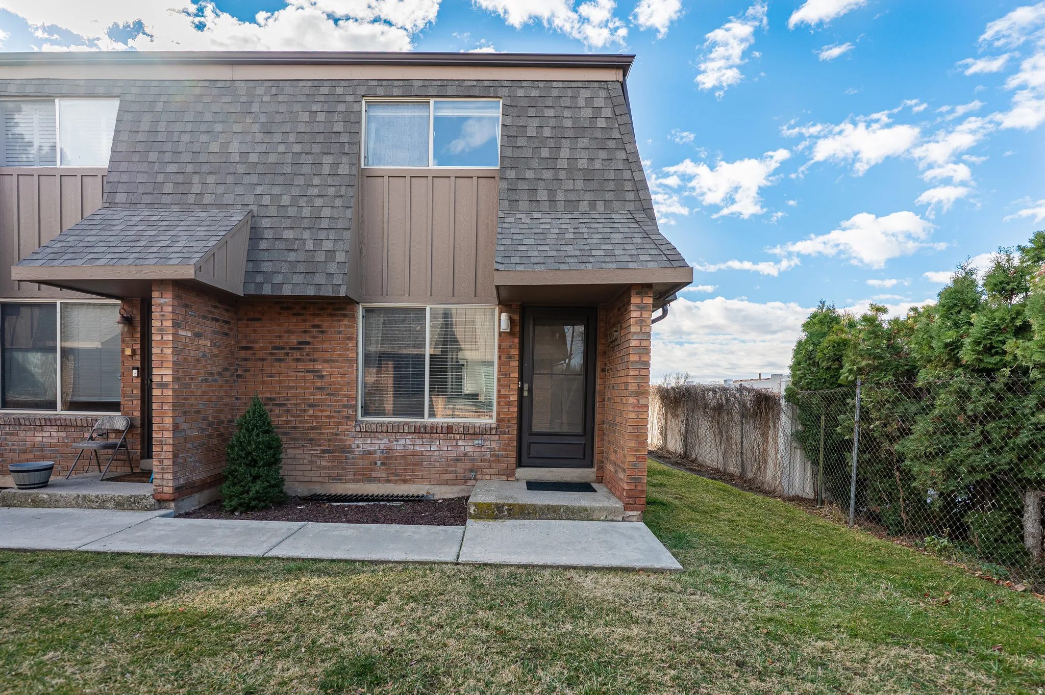 View of front of home with brick siding, roof with shingles, and board and batten siding