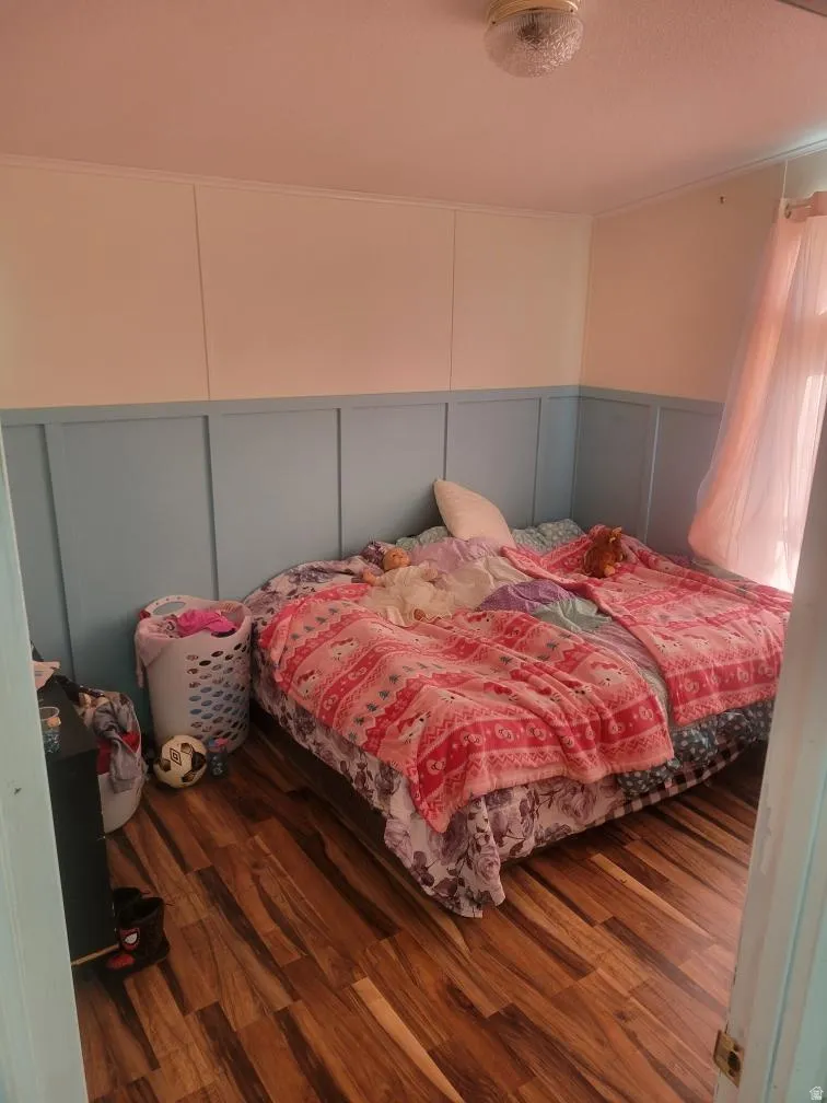 Bedroom featuring a decorative wall and dark wood-type flooring